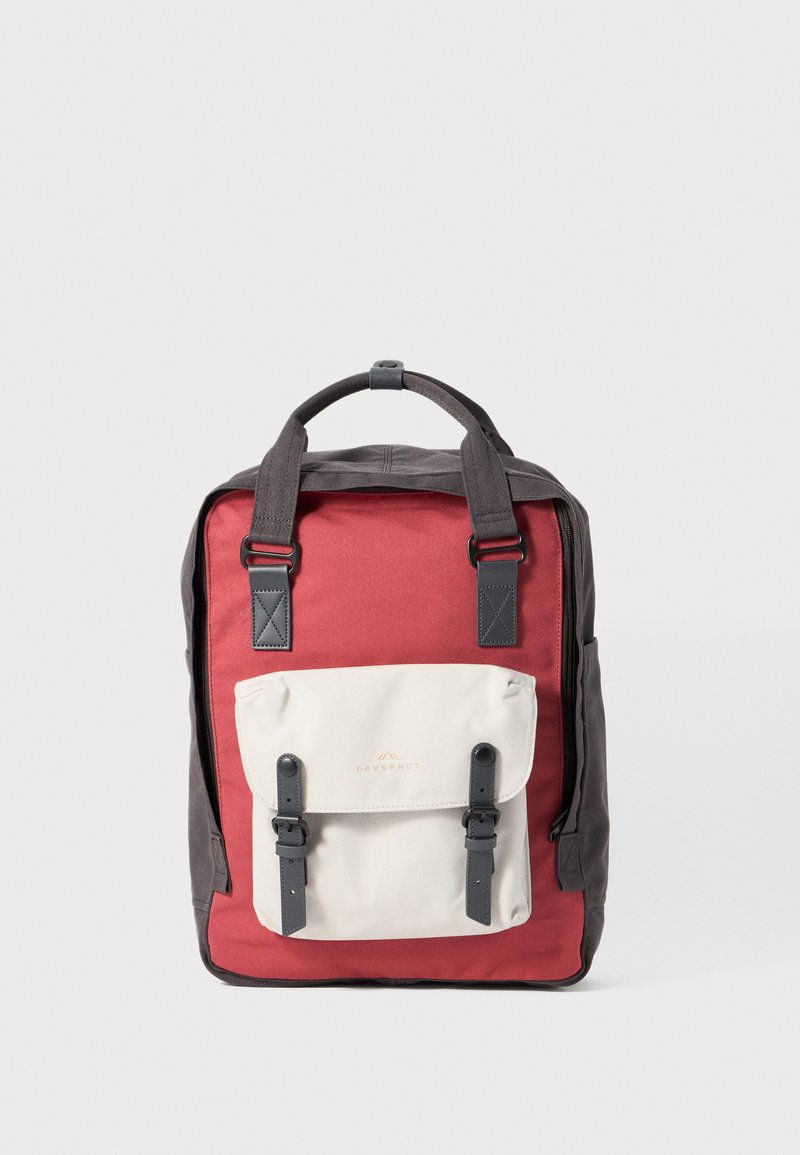 Ryggsäck med röd kropp och mörkgrå bas, med en beige frampocket som har remmar och spännen, tillverkad av slitstarkt tyg.