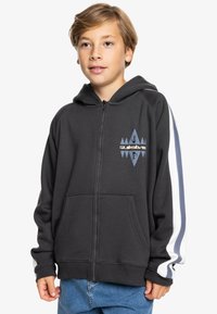 Sudadera con cremallera en gris, con acentos de rayas blancas y azules en las mangas, que presenta un logo gráfico en el pecho y bolsillos frontales.