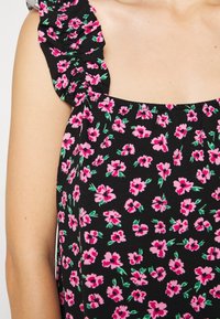 Top floral preto com flores cor-de-rosa e folhas verdes, alças com babados e decote quadrado. Feito em tecido suave com um design ajustado.