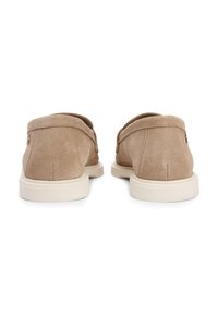 Μπεζ σουέντ παπούτσια slip-on με στρογγυλεμένη πίσω όψη, λευκές λαστιχένιες σόλες και λεπτομέρεια με ελάχιστο ράψιμο. Ομαλή υφή με διακριτική γυαλάδα.