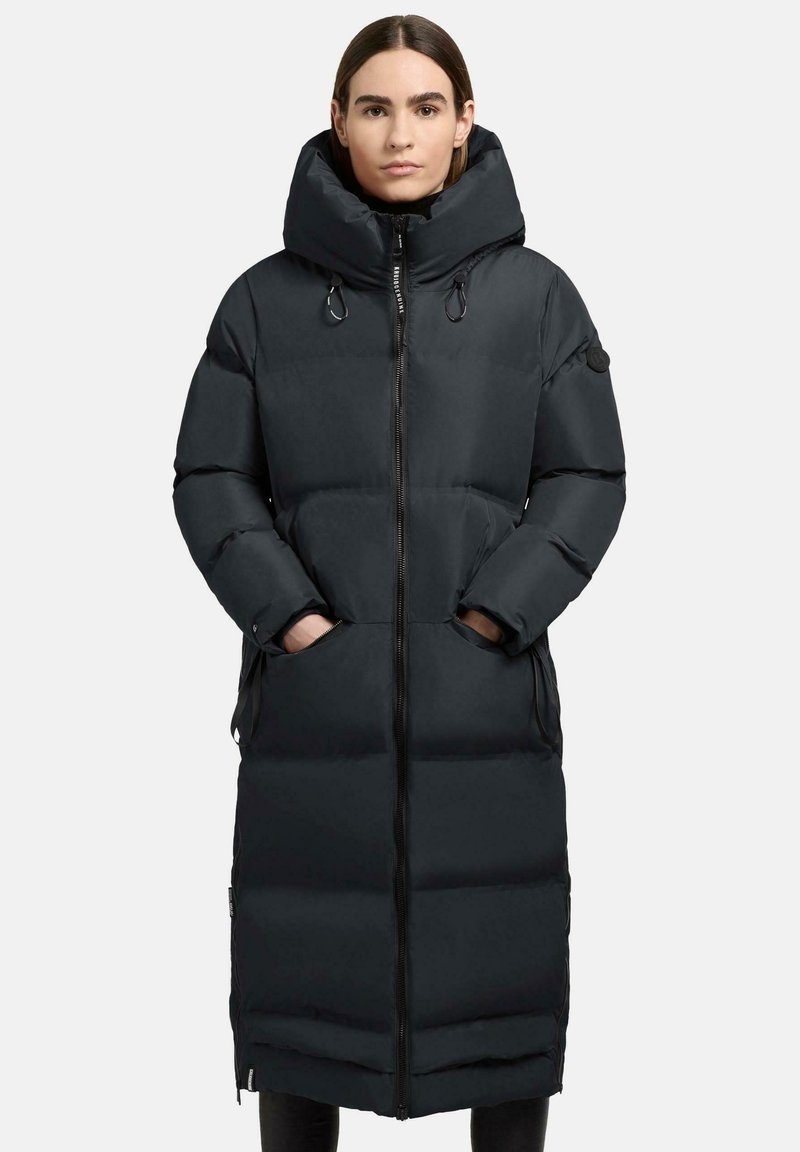 Lunga giacca a vento nera con collo alto, chiusura con zip, grandi tasche e texture trapuntata. Presenta una silhouette aderente e un cappuccio oversize.
