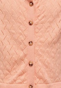 Cardigan lavorato a maglia pesca con un motivo testurizzato a zigzag, otto bottoni rotondi con finitura lucida disposti al centro.