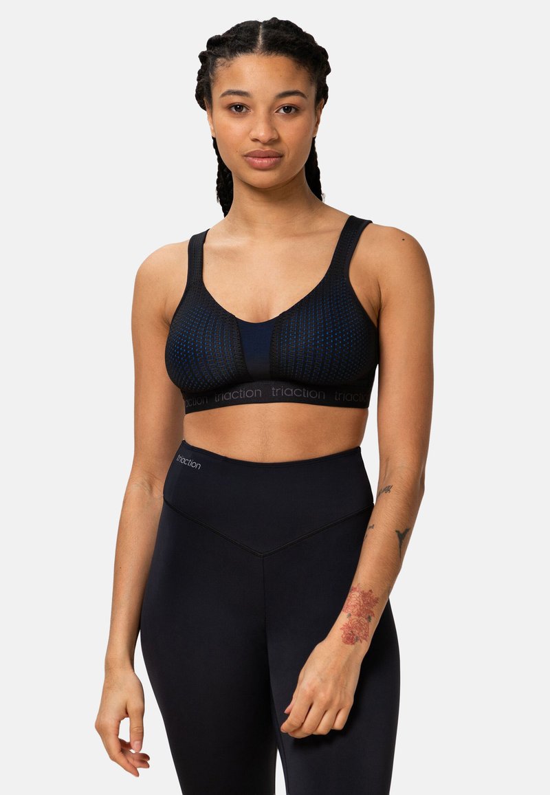 Brassière de sport noire avec un design texturé et des bretelles larges, associée à des leggings noirs taille haute. Détail de la ceinture avec logo.