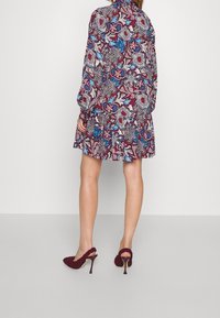 Květinové šaty v několika barvách s burgundským pozadím, dlouhými rukávy a sklady na sukni. Nosené s vysokými podpatky v burgundské textuře.