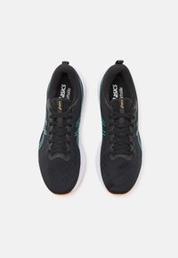 Chaussures de sport noires avec une tige en mesh, semelle en caoutchouc blanche et accents teal sur les côtés. Possède des lacets ronds noirs et une languette rembourrée.