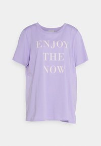 Lilla kortærmet t-shirt lavet af blødt stof, der har teksten "NYD NUET" i cremefarve på forsiden. Rund halsudskæring og afslappet pasform.