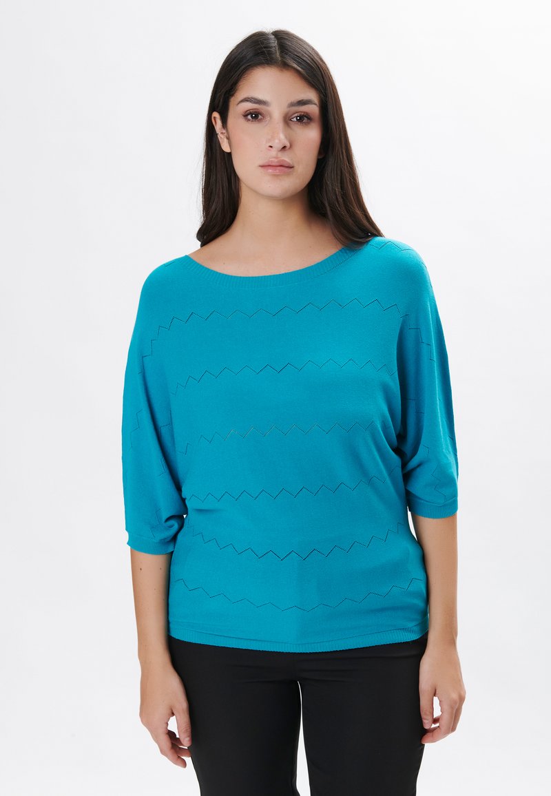 Maglione turchese con scollatura a barca, maniche a tre quarti e motivo a zigzag. Tessuto morbido e leggero, vestibilità rilassata.