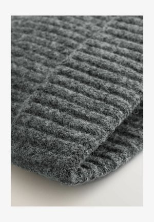 Pilkas mezginys su raukšlėtu paviršiumi, minkštas ir pūkuotas, sulenktas trikampio forma, demonstruojantis storį ir sudėtingą raštą.