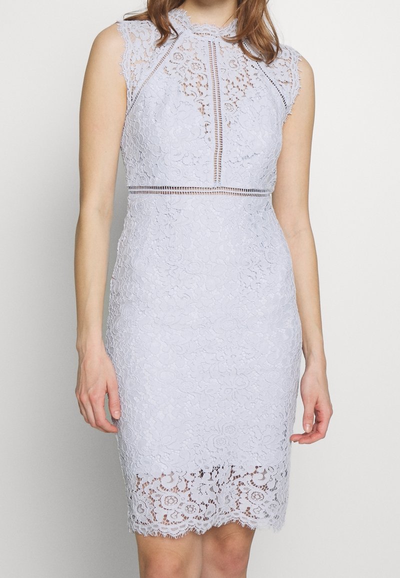 Krajkov dress v světlé modré barvě, bez rukávů, s květinovými vzory, vysokým výstřihem, přiléhavým střihem a detailním vlnitým lemem.