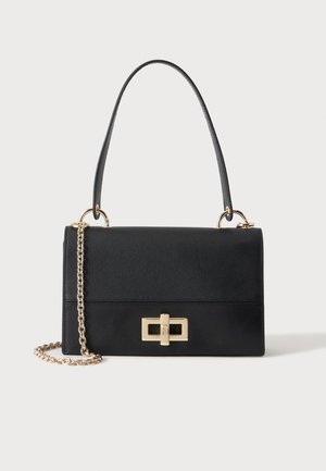 Sac à main en cuir noir avec une poignée supérieure, une bandoulière chaîne dorée et un fermoir à torsion rectangulaire doré sur le devant.