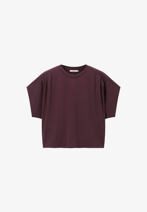 Haut bordeaux à manches courtes en coton doux. Présente une coupe décontractée avec des plis aux épaules, un col rond et une texture lisse.