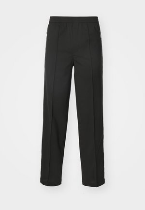 Pantalons noirs en tissu extensible, à coupe droite, avec poches zippées sur les côtés et texture lisse sans motifs visibles.