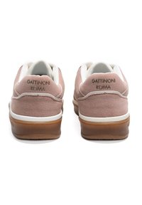 Rosa mockaskinnsnickers med vita accenter, som har en brun gummisula, hälvaddering och präglad logotyp på hälfliken.