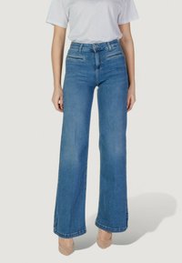 Jeans de tiro alto en un azul claro, con un diseño de pierna ancha. Presentan dos bolsillos delanteros y costuras visibles a lo largo de los dobladillos. Tela de denim texturizada.