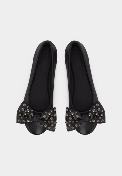 Μαύρα μπαλαρίνες με στρογγυλεμένες μύτες, κάθε ζευγάρι διαθέτει ένα διακοσμητικό φιόγκο με καρφιά στην κορυφή, τοποθετημένα πλάι-πλάι σε λευκό φόντο.