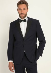 Marine tuxedo jack met zwarte satijnen revers, enkele knoopsluiting en zakdetail; gecombineerd met een witte shirt en zwarte vlinderdas.