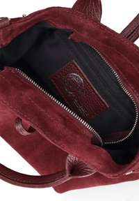 Borsa in suede bordeaux con manici in pelle, apertura con zip nella parte superiore e rivestimento interno nero con etichetta in pelle "Made in Italy".