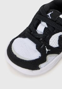 Baskets noires et blanches avec une tige en mesh, des accents en daim, des lacets texturés et une semelle en caoutchouc avec un logo.