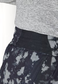 Grå heather skjorte lagdelt over svarte og grå tie-dye joggebukser, med elastisk midjebånd og teksturert stoff med en glatt overflate.