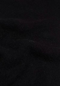 Tessuto a maglia nero, morbido al tatto con un motivo a costine, che presenta sfumature diverse di nero in leggere pieghe. Nessun hardware o accentuazione notevole.