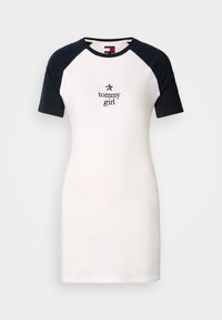 Kjole med korte ermer laget av bomull, med en hvit kropp og svarte raglanermer, og "tommy girl" brodert på forsiden i mørkeblått.