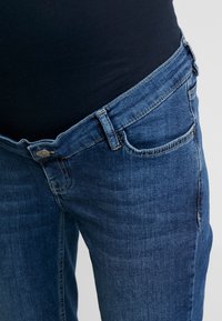 Denim jeans in dark blue with a slim fit. Features include a front button, a single front pocket, and subtle fading on the fabric.