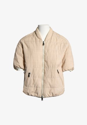 Lyse beige kortærmet quiltet jakke med frontlynlås og to lynlåslommer, vist på en hvid mannequin-torso.