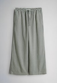 Zwart-wit geruite wijde broek met elastische tailleband en trekkoord, getoond tegen een effen grijze achtergrond.