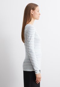 Langermet topp i myk, lett stoff. Har horisontale lysegrå og hvite striper. Tilpasset silhuett med rund hals.