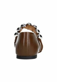 Chaussure plate en cuir marron avec un bout rond et une semelle noire. Des clous en argent notables ornent l'arrière, ajoutant un élément décoratif.