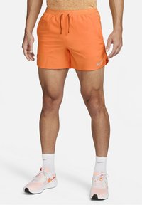 Oranssit Nike-juoksushortsit, joissa on joustava vyötärö, nyöri ja pieni logoaksentti. Sujuva kangas ja polven yläpuolelle ulottuva leikkaus.