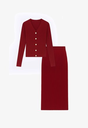 Czerwony prążkowany sweter na guziki z dekoltem w serek, zestawiony z dopasowaną, prążkowaną ołówkową spódnicą. Oba elementy mają dopasowany fason.