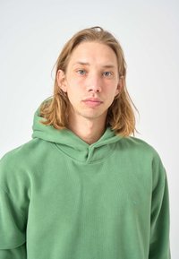 Green cotton hoodie with a front pocket, adjustable drawstring hood, and subtle logo detail on the chest. Smooth texture and relaxed fit.
