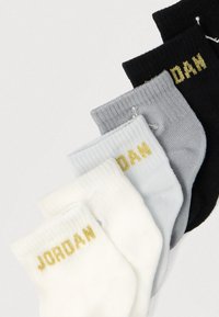 Bawełniane skarpety za kostkę w kolorach czarnym, szarym, jasnoszarym i białym, z złotym logo „JORDAN” na ściągaczach. Żebrowana faktura, długość do połowy łydki.