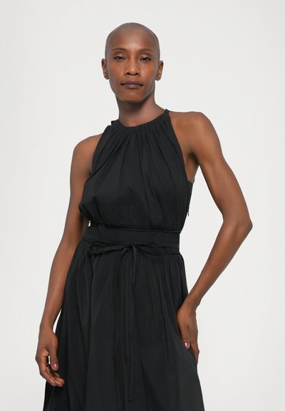 Rochie halter neagră cu corp pliat, talie strânsă și legătură ajustabilă. Țesătură fluidă cu buzunare laterale și o siluetă lejeră.