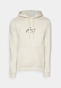 Sudadera con capucha de color beige claro, hecha de una tela suave, que cuenta con un bolsillo tipo canguro en el frente y un logo impreso en negro en el pecho.