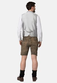 Grauer Satin-Weste mit einem gemusterten Kragen, getragen über einem weißen Langarmshirt. Braune Lederhosen und schwarze knielange Socken runden den Look ab.