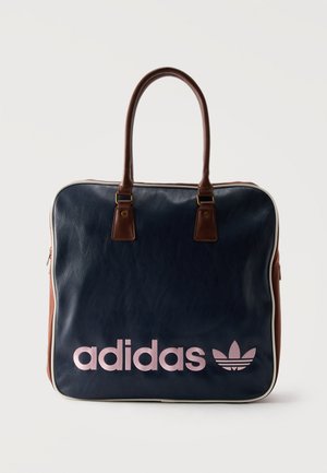 Tote torba adidas iz temno modre in rjave usnjene kože z rjavimi ročaji, belim robom ter roza adidas logotipom in deteljico spredaj.