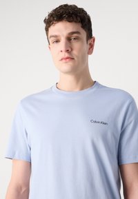Lyseblå kortærmet t-shirt lavet af bomuld, med rund halsudskæring og et lille sort "Calvin Klein" logo på brystet.