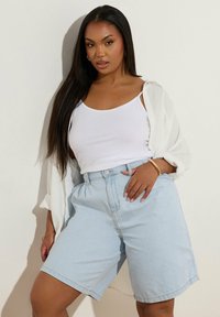 Shorts in denim azzurro chiaro con una vestibilità comoda, vita alta e tasche laterali. Abbinati a una canotta bianca e a una camicia bianca leggera e ampia.