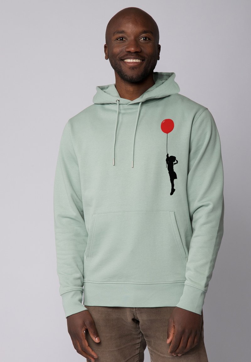Lichtgroene hoodie met een voorzak, met een zwarte silhouette van een kind dat een rode ballon vasthoudt. Gemaakt van zachte, gestructureerde stof.