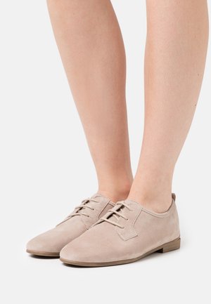 Béžové sukně šněrovací boty s kulatou špičkou, nízkým podpatkem a kontrastním prošíváním. Hladký povrch a minimalistický design.
