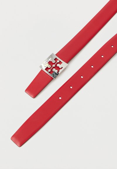 Κόκκινη δερμάτινη ζώνη με ασημένιο τετράγωνο αγκράφα που διαθέτει κομμένο γεωμετρικό σχέδιο και πολλές τρύπες ρύθμισης σε λευκό φόντο.