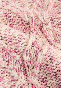 Gehaakte dekentje in crème met roze en paarse draad. Heeft een textuurpatroon met verhoogde kabeldetails. Zacht, gezellig materiaal.