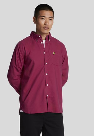 Chemise boutonnée bordeaux en mélange de coton, avec une poche poitrine et un petit logo jaune. Manches longues avec col, coupe décontractée.