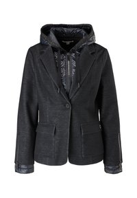 Veste noire cintrée superposée sur une doudoune noire brillante à capuche zippée, avec poches avant et détails de fermeture éclair aux manches.