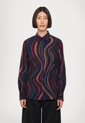 Chemise à manches longues avec un motif de vagues en noir, rose, rouge et bleu, dotée d'un col boutonné et de boutons violets. Tissu doux au toucher.