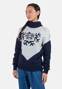 Marineblauer und hellgrauer Wollpullover mit hohem Kragen, der mit Schneeflockenmuster und einem Logo auf der Brust versehen ist. Gerippte Bündchen und Saum.