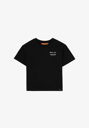 Czarna koszulka z krótkim rękawem i okrągłym dekoltem, z białym napisem „Reiss 1971 McLaren Formula 1 Team” na lewej piersi oraz małą metką z logo na dole.
