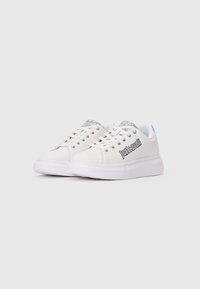 Weiße Sneaker mit glattem synthetischen Obermaterial, glitzernden Akzenten auf der Zunge und einer dicken weißen Gummisohle. Mit Logodetail an der Seite.